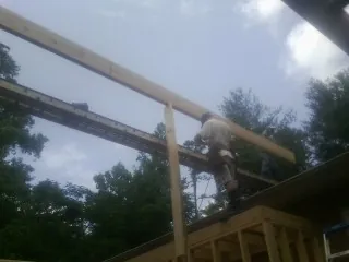 Carpenter setting a ridge beam over a new addition frame — Ice Dam Removal by Roofing Brothers in Watertown
