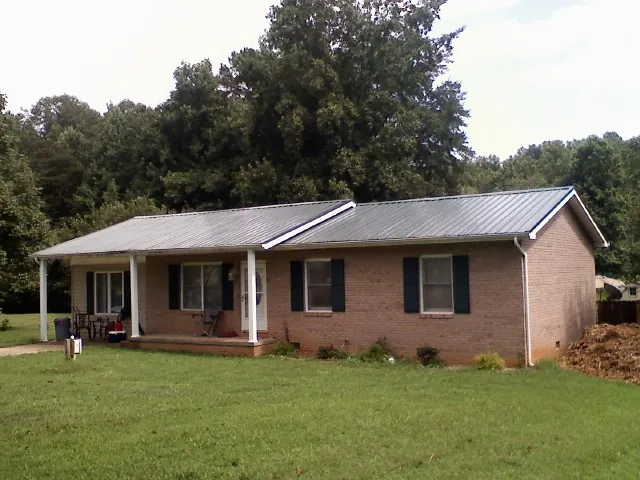 Gray metal roof on a brick ranch house with a side carport in Watertown