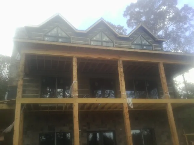 Dormers and porch framing on a large log home under construction — Roof Coating work by our crew in Watertown