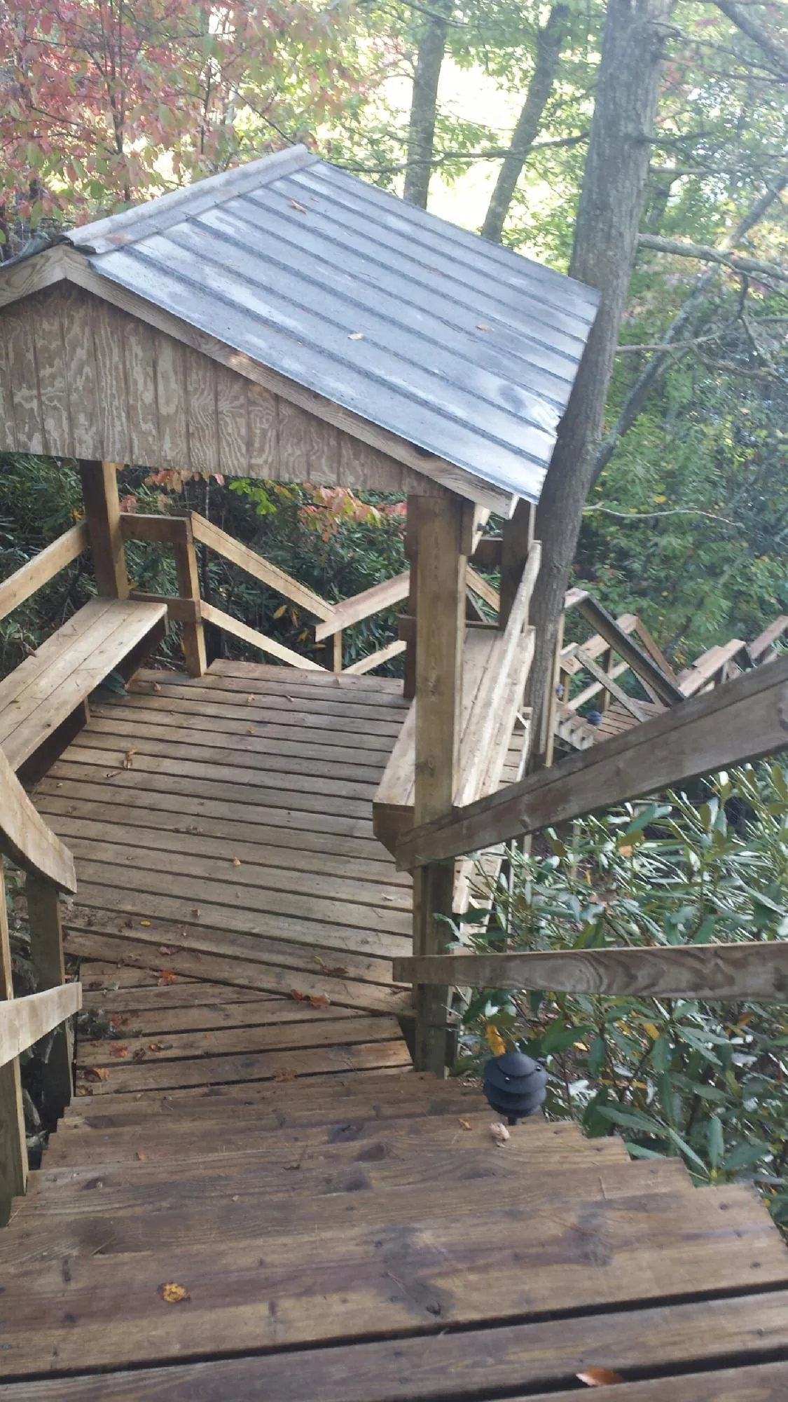 Metal roofed shelter over wooden steps on a wooded walkway — Skylight Repair & Installation work by our crew in Watertown